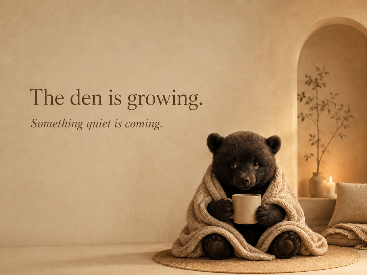 Nao wrapped in a cream blanket holding a mug in a quiet Cozy Den interior.